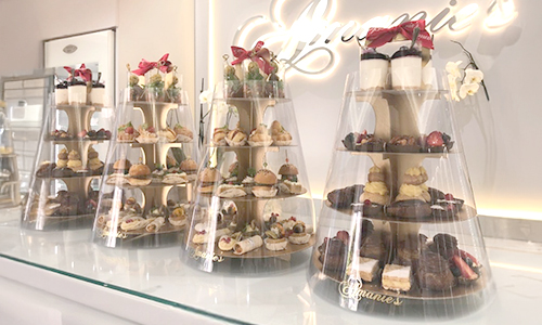 Assorted savory bites displayed on tiered stands, including sliders, wraps and pastries.